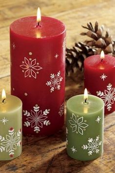 three candles with snowflakes on them sitting next to a pine cone and cones