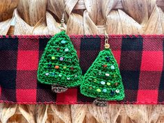 two green crocheted christmas trees hanging from red and black plaid fabric with gold ear wires