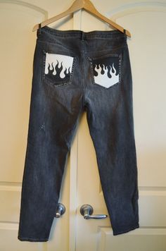 a pair of jeans with flames painted on them hanging from a hanger in front of a door