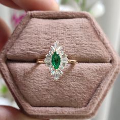 a close up of a person holding a ring in their hand with a green stone on it