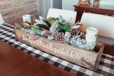 a wooden box filled with pine cones and greenery sitting on top of a table