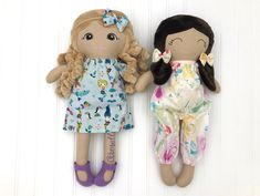 two dolls sitting next to each other on a white wall with one holding the other's hand