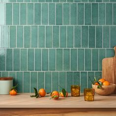 there are oranges on the counter next to glasses and a cutting board in front of them