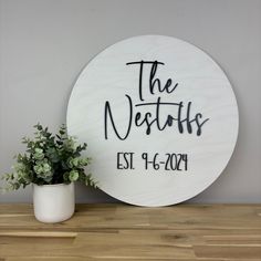 a sign that says the nesties is next to a potted plant on a wooden table