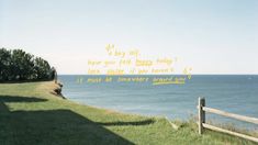 a wooden fence sitting on top of a lush green hillside next to the ocean with words written in cursive writing