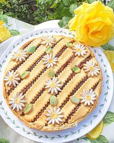 a cake decorated with flowers and leaves on a plate next to some yellow rose petals