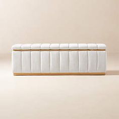 a white bench sitting on top of a floor next to a beige wall and wooden frame