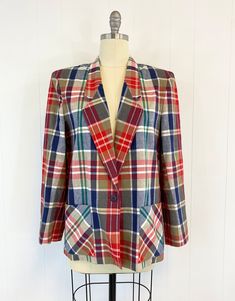 "80s plaid blazer with pockets featuring; ~ a notched lapel shoulder pads long sleeves single, navy blue button closure at the waist patch pockets at the hip hem hits low on hip boxy cut ~ of a smooth, mid weight, cotton in a large scale plaid in red, navy blue, kelly green, khaki and white ~ labeled \" Country Suburbans\", is made in the USA and is tagged a size 16, measurements when laid out flat are: 23 inches from pit to pit 24 1/2 inch sleeve 21 inches across bottom opening 28 1/2 inches fr Retro Workwear Blazer With Welt Pockets, Retro Blazer With Welt Pockets For Work, Plaid Blazer With Patch Pockets For Fall, Vintage Blazer With Patch Pockets For Work, Fall Plaid Blazer With Patch Pockets, Vintage Workwear Blazer With Patch Pockets, Retro Plaid Blazer For Work, Vintage Blazer With Patch Pockets And Long Sleeves, Plaid Wool Blazer With Patch Pockets