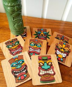 four wooden coasters with cartoon faces on them sitting on a table next to a green vase