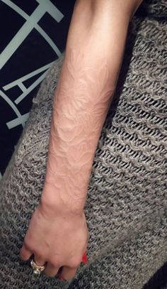 a woman's arm with a small tattoo on the left side of her arm