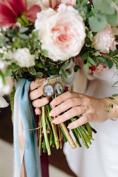 a woman holding a bouquet with flowers and an old watch on it's wrist