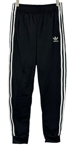 Add style and comfort to your athletic wardrobe with these black and white Adidas Superstar SST Track Jogger Pants in size L. Featuring an elastic waist with adjustable drawstring closure, these pants are perfect for travel, casual wear, and various sports activities such as soccer, hiking, and yoga. Made from polyester blended fabric, these pants offer easy care and are machine washable. The solid black color with Adidas stripes pattern adds a touch of sophistication to your outfit, while the tapered leg style and 26-inch inseam provide a great fit. These pants are perfect for boys who love comfort and style. White Adidas Superstar, Black And White Adidas, Adidas Pants, Sports Activities, White Adidas, Boys Who, Jogger Pants, Stripes Pattern, Track Pants