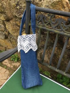 a blue purse sitting on top of a green table next to a metal fence and stone wall