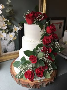 a wedding cake decorated with red roses and baby's breath