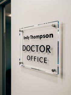 a doctor office sign hanging on the wall next to a glass plaque that reads, family thompson