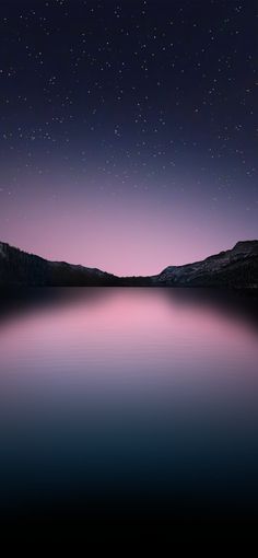 the night sky is lit up with stars above water and mountains in the distance,