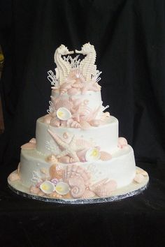 a wedding cake decorated with shells and seahorses