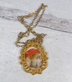 Sweet woodland mushroom pendant. Image of a red mushroom with white dots is set in a vintage style gold plated pewter setting. Sealed in resin for a glass like appearance. Lead and nickel free gold plated chain. 17 5/8" end to end. Pendant hangs an additional 1.5". Vintage Gold Resin Jewelry, Vintage Gold Necklace With Pressed Flowers, Red Cameo Necklace For Gift, Retro Glass Necklace For Gifts, Vintage Red Resin Jewelry, Vintage Resin Necklace As Gift, Vintage Resin Necklace For Gift, Retro Resin Jewelry Gift, Retro Resin Jewelry For Gifts