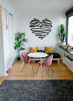 a living room filled with furniture and a white table surrounded by pink chairs next to a window