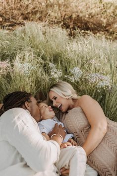 a woman and two men are laying on the ground with a baby in their lap