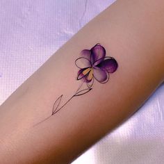 a purple flower tattoo on the left inner arm and lower arm, with yellow tips