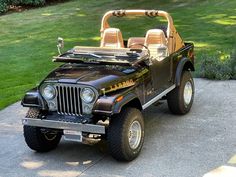 the jeep is parked on the side of the road in front of some grass and bushes