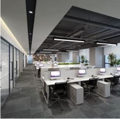 an office with multiple desks and computers on each side of the room, along with planters