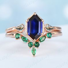 a close up view of a ring with an emerald and blue stone in the center