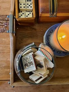 a candle and some dices on a table next to a box with playing cards