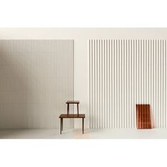 a chair sitting in front of a white wall next to a tall wooden piece of furniture