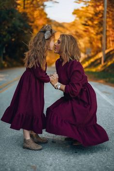 two women in long dresses are kissing each other on the side of an empty road