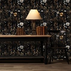 a table with books and a lamp on it in front of a floral wallpaper