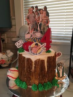 a birthday cake with the number four on it, decorated like a tree stump and baseballs