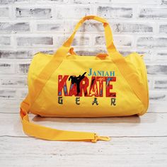 "Get your kicks on with this yellow duffle bag with red and teal accents. Shown with girl (with ponytail) karate silhouette, boy design available on request. ABOUT THIS Duffel: 🐉 Choose from a large duffel - 24\", small duffel - 18\", or 16x18\" zipper top tote. 🐉 Embroidered on a denier polyester bag- Made with 50% recycled material. Small bag has a single zippered main compartment, with a diagonal webbing handle and detachable adjustable barrel shoulder strap. Large bag also has a side zippe Red Rectangular Duffle Bag For School, Retro Yellow School Bag, Retro Yellow School Bags, Functional Yellow Sports Bag, Karate Silhouette, Karate Gear, Karate Gifts, Black Duffle Bag, Boy Design