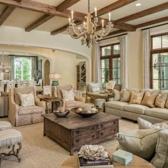 a living room filled with lots of furniture and a chandelier hanging from the ceiling