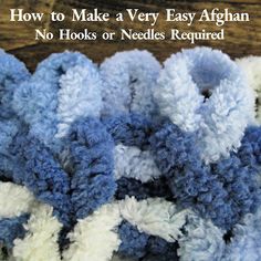 a pile of blue and white crocheted flowers on top of a wooden table