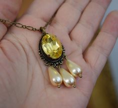 This necklace features an elaborate filigree setting with a large 18mm Aurora Crystal focal stone in a Citrine yellow with three creamy glass pearl dangles. The delicate chain is 18" long. Best for Regency, Victorian, or Edwardian use. Antique Gold finish Note that this can be custom ordered in many colors! Please contact me (taylor@damesalamode.com) for customization options! Victorian Style Yellow Gold Locket Necklace, Ornate Gold Necklace With Pearl Pendant, Victorian Yellow Gold Jewelry With Large Pendant, Victorian Yellow Gold Necklace With Pearl Pendant, Yellow Filigree Pendant Jewelry, Delicate Chain, Cross Pendant Necklace, Silk Ribbon, Cross Pendant