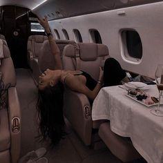 a woman laying on the back of an airplane next to a table full of food