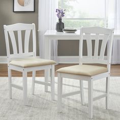 two white chairs sitting next to each other in front of a table