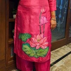 a woman standing in front of a door wearing a pink dress with flowers on it