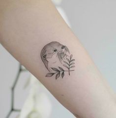 a small otter tattoo on the left inner forearm and arm, with leaves around it