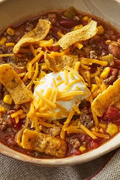 a bowl filled with chili, cheese and tortilla chips on top of a table