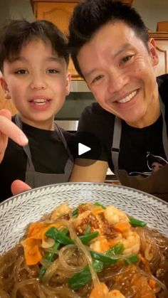 a man and boy posing for a photo in front of a bowl of noodles with vegetables