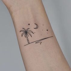 a small palm tree and moon tattoo on the left inner arm, with stars in the sky above it