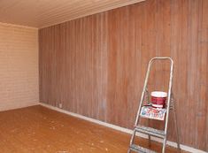 an empty room with a ladder and paint buckets on the floor next to it