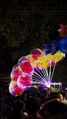 balloons are being blown by people in the dark at an outdoor event with lights on them