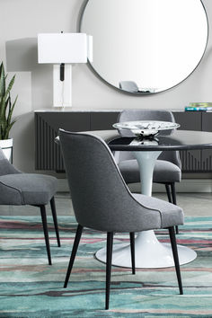 a round dining table with four chairs around it and a circular mirror on the wall