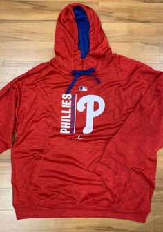 a red philadelphia phillies hoodie with the word'p'on it sitting on top of a wooden floor