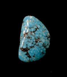 a large turquoise stone with brown spots on it's surface, against a black background