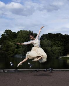 a woman is jumping in the air with birds around her